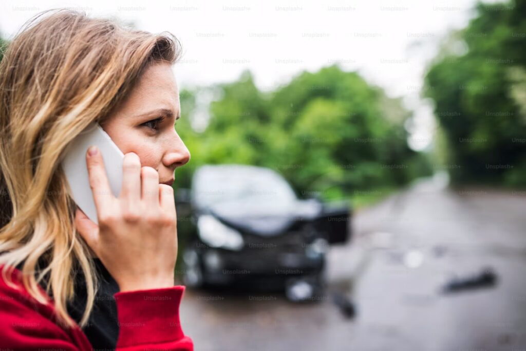 Dit is een foto van een vrouw die schade heeft aan een voertuig en telefonisch contact opneemt